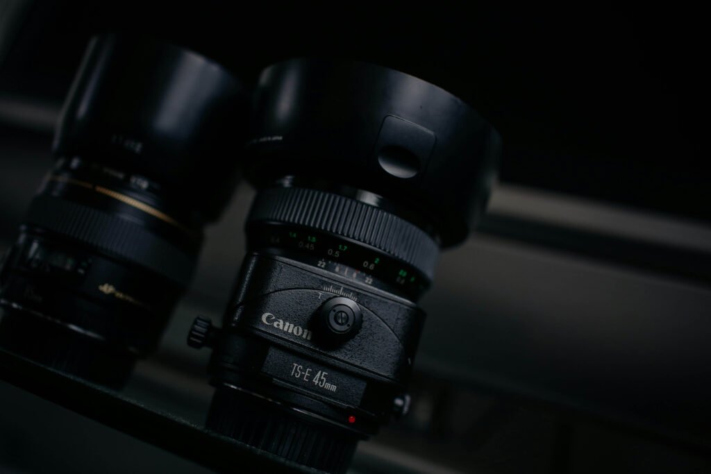 Two Canon Camera Lenses Laying On Something Dark, Black Background